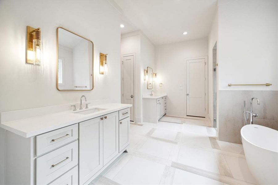 Dual vanities are decorated with white quartz, pendant lighting, and white porcelain tiled walls.