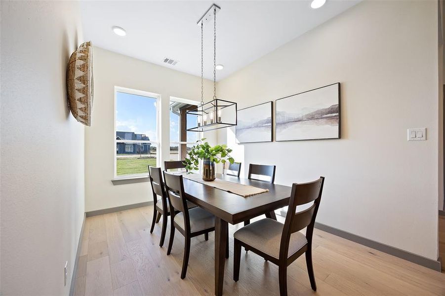 Dining room with light hardwood / wood-style floors and a notable chandelier