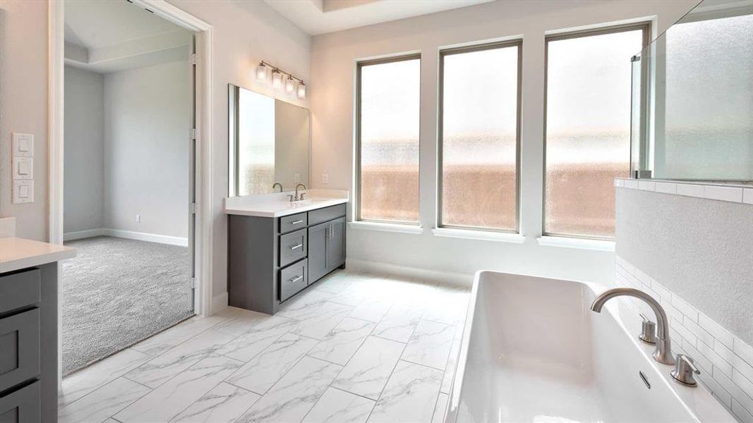 Bathroom with vanity, a washtub, tile patterned flooring, and plenty of natural light