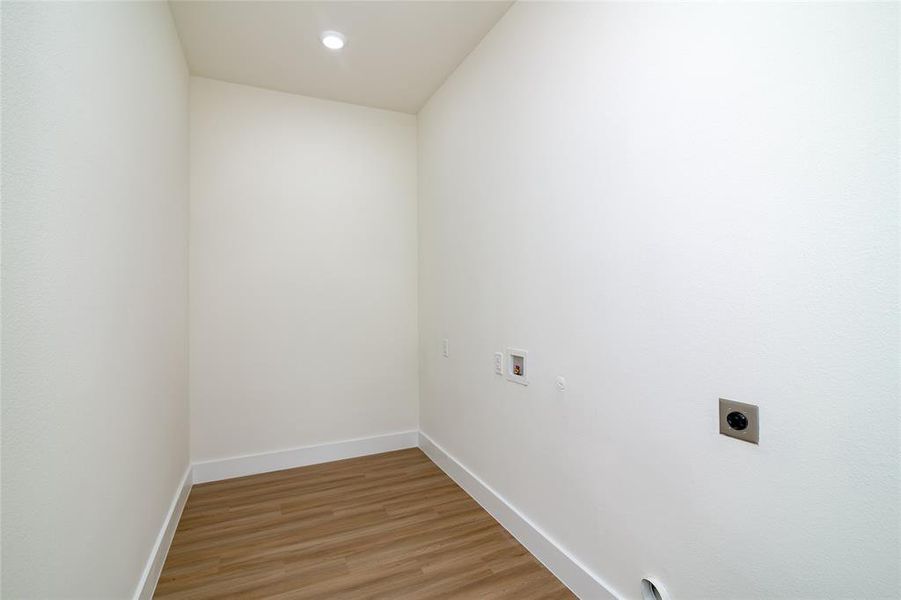 Clothes washing area with light hardwood / wood-style flooring, hookup for an electric dryer, and washer hookup