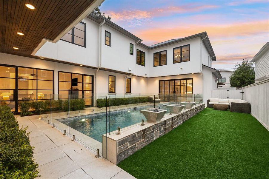 The backyard serves as a relaxing oasis throughout the year, featuring artificial turf and exquisite landscaping, complemented by a custom glass-enclosure, heated saltwater pool and spa, adorned with stackstone wall with three cascading waterfall features.