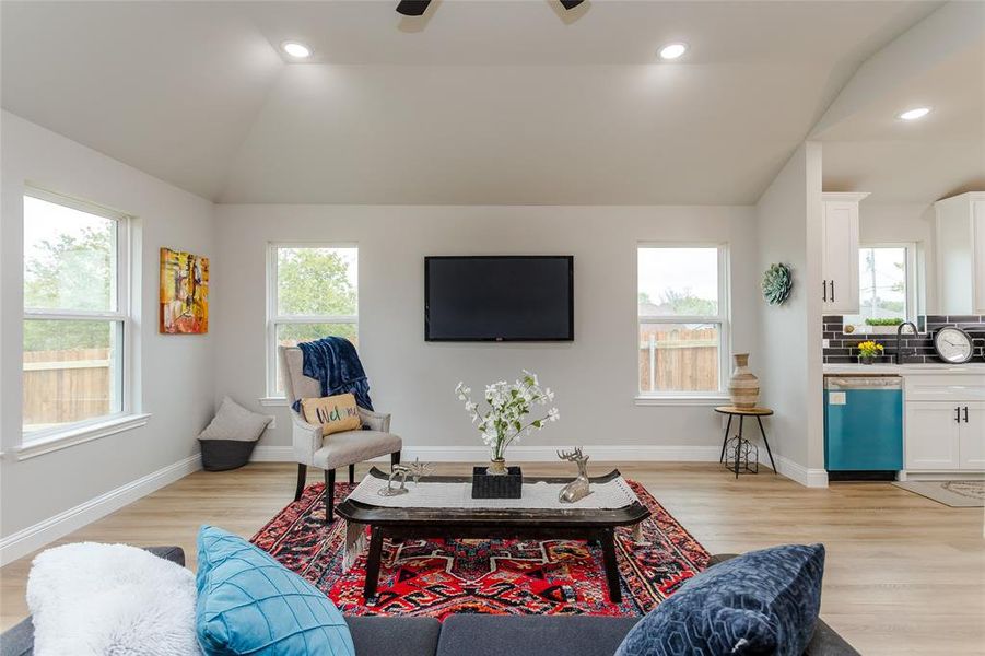 Living room with light hardwood / wood-style floors, lofted ceiling, and plenty of natural light