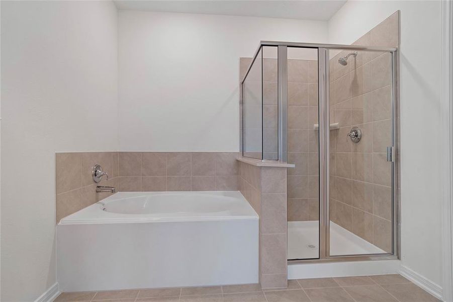 The additional view of the primary bathroom displays the separate garden tub and walk-in shower with tile surround.