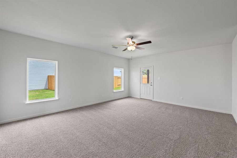 Carpeted living room with ceiling fan and plenty of natural light