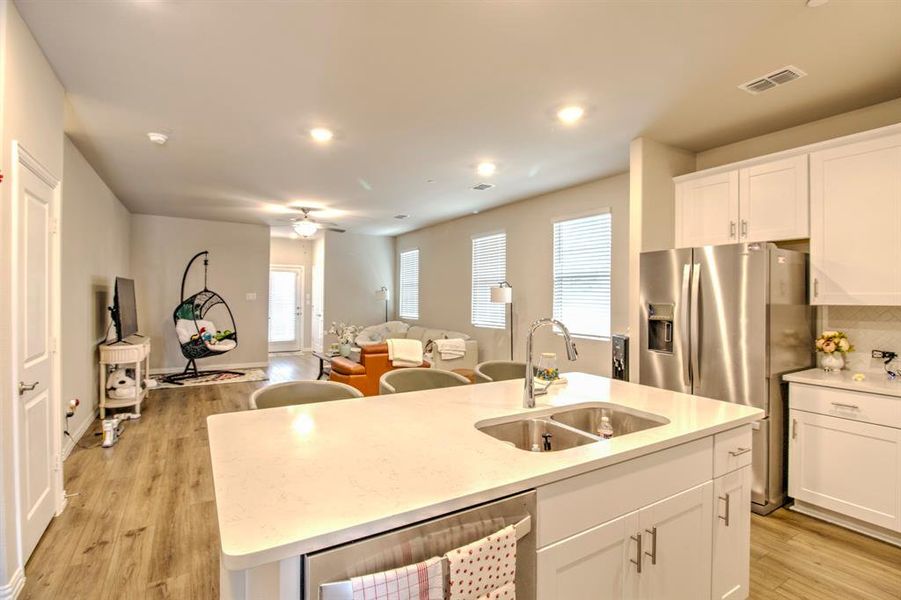 Kitchen featuring a center island with sink, light hardwood / wood-style flooring, white cabinets, sink, and ceiling fan