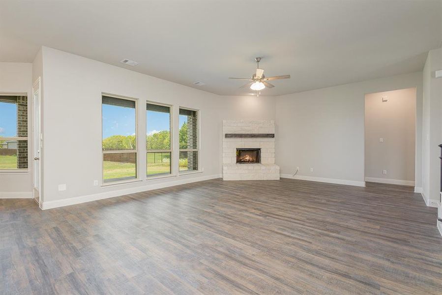 Unfurnished living room featuring ceiling fan, a fireplace, and dark hardwood / wood-style flooring