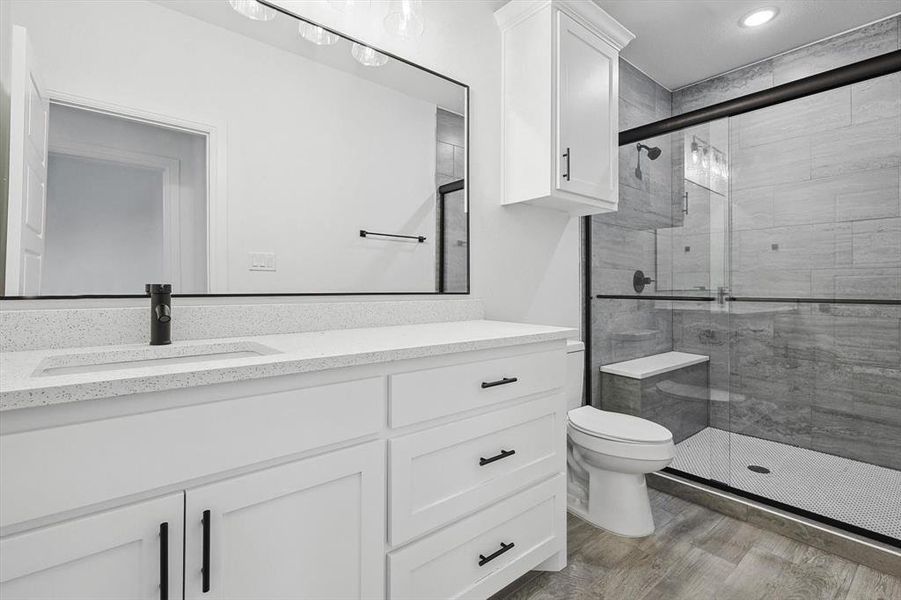 Bathroom with hardwood / wood-style flooring, vanity, a shower with door, and toilet