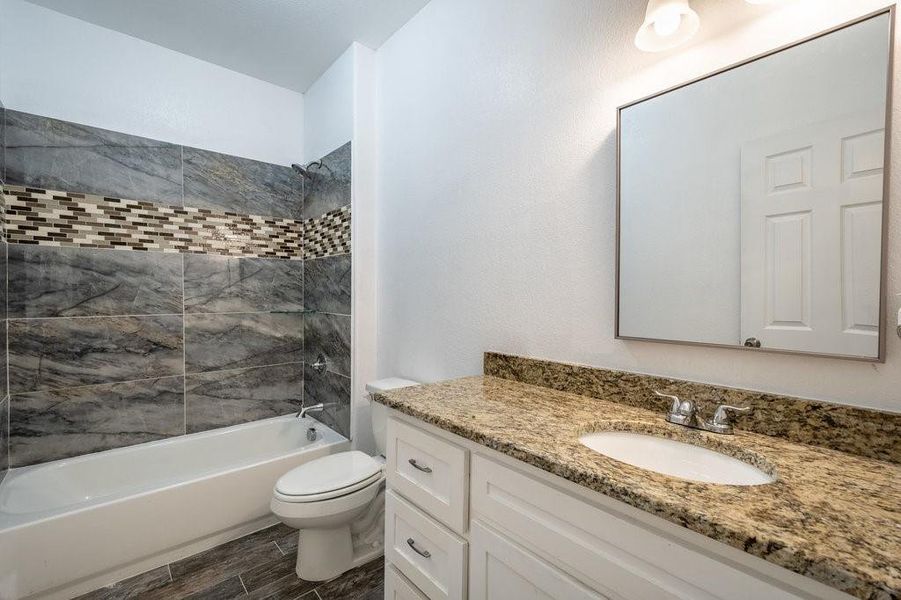 Spacious bathroom with custom tile and granite counter top.
