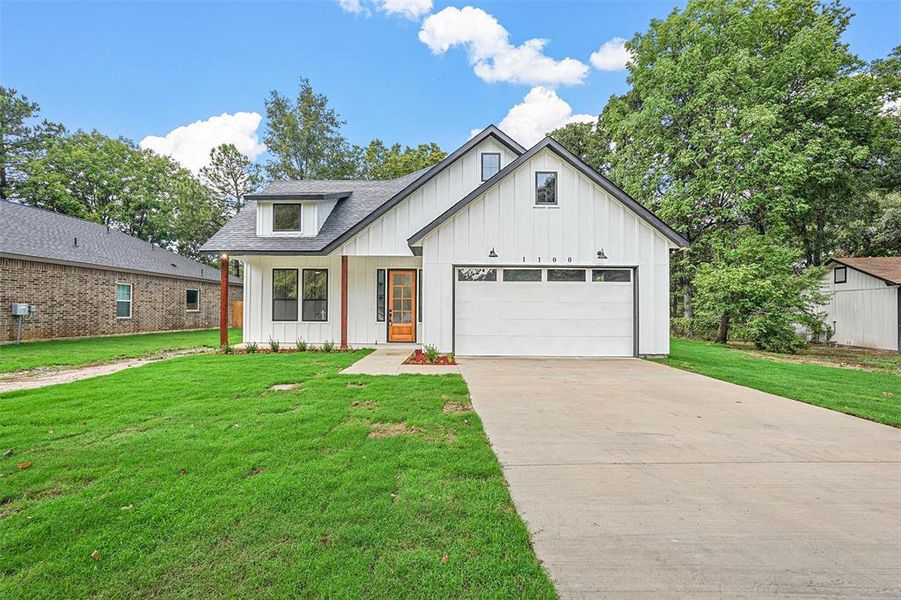 Modern farmhouse style home with a garage and a front yard