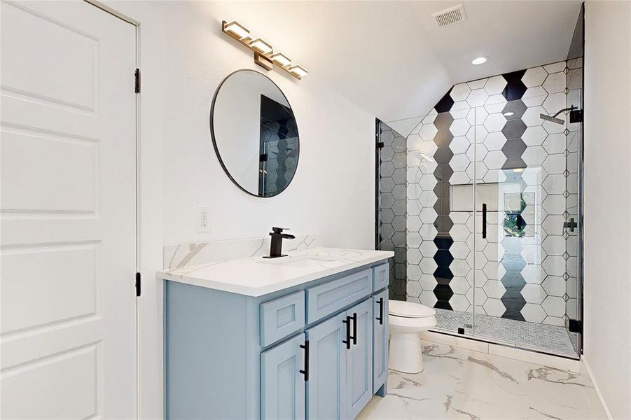 Bathroom with a shower with shower door, vaulted ceiling, tile patterned floors, toilet, and vanity