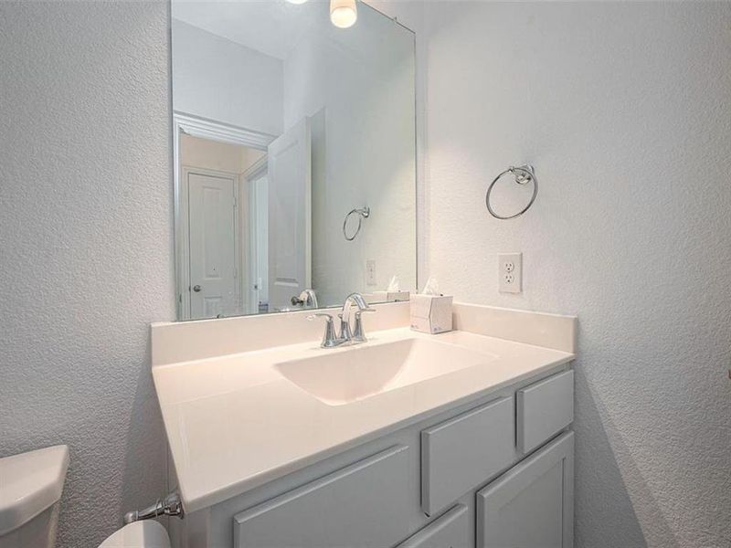 This bathroom features a granite countertop, a sleek faucet, and a large mirror, creating a modern and elegant look.