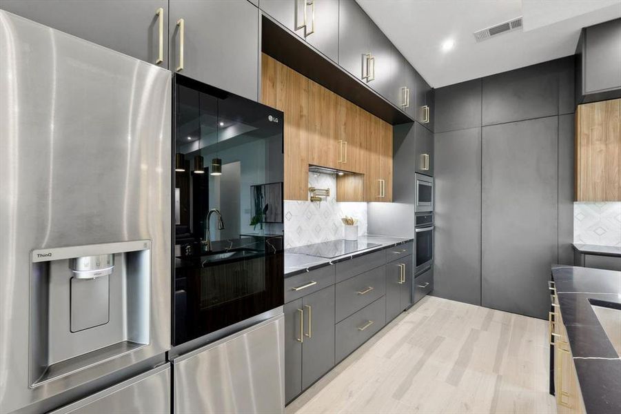 Kitchen featuring decorative backsplash, light wood-type flooring, extractor fan, and stainless steel appliances