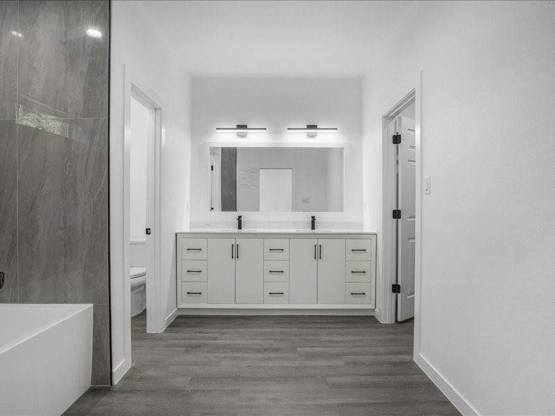 Bathroom with hardwood / wood-style flooring, double sink vanity, and toilet