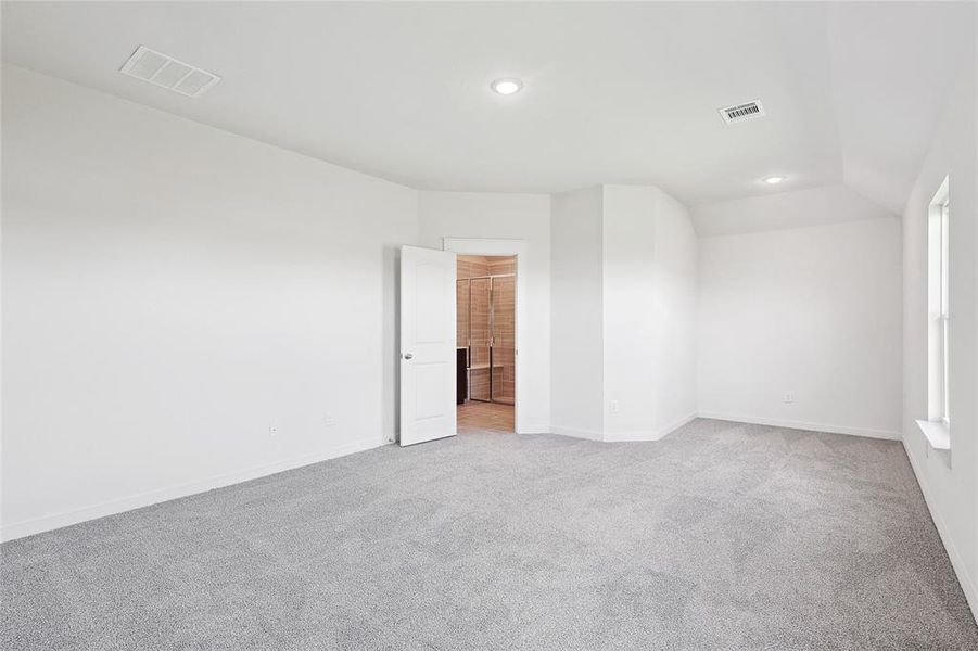 Spare room featuring light carpet and vaulted ceiling