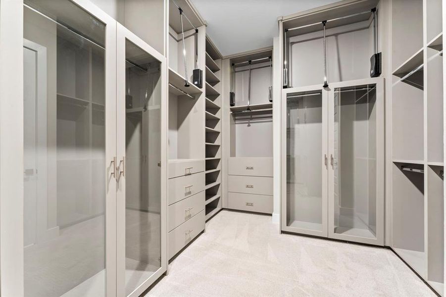 Spacious custom primary closet featuring a glass cabinet and ample storage to meet all your organizational needs.