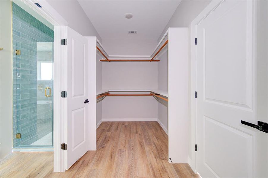 Large walk-in primary closet with direct access to the laundry room.