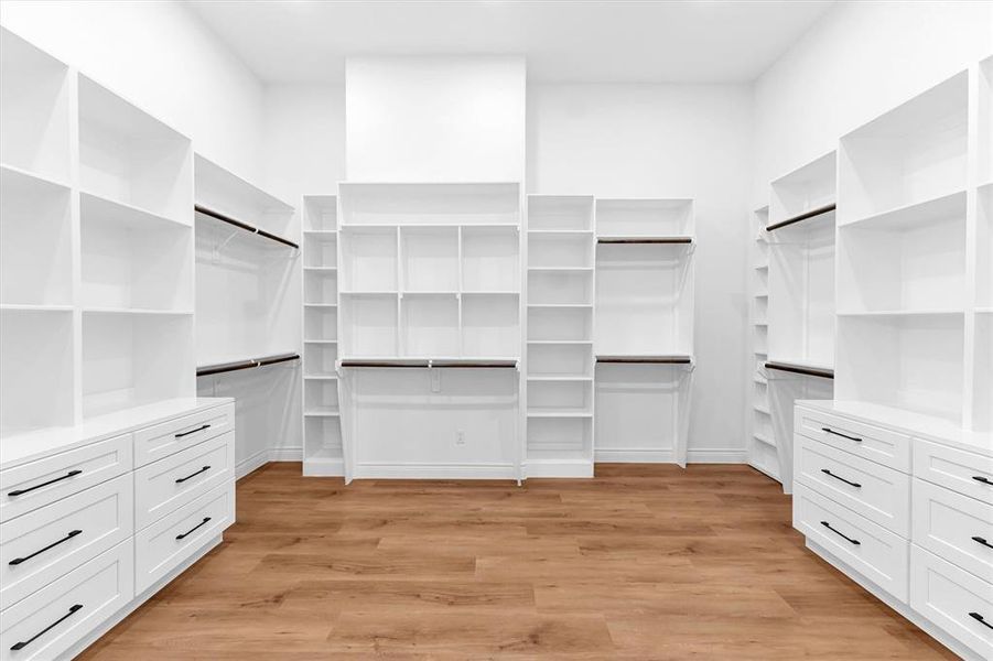 Spacious and smartly designed walk-in closet off the primary bath with built-in shelving, drawers and hanging rods in the primary closet.