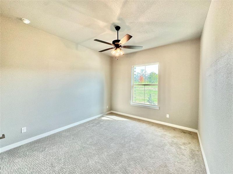 Carpeted secondary room featuring a textured ceiling and ceiling fan