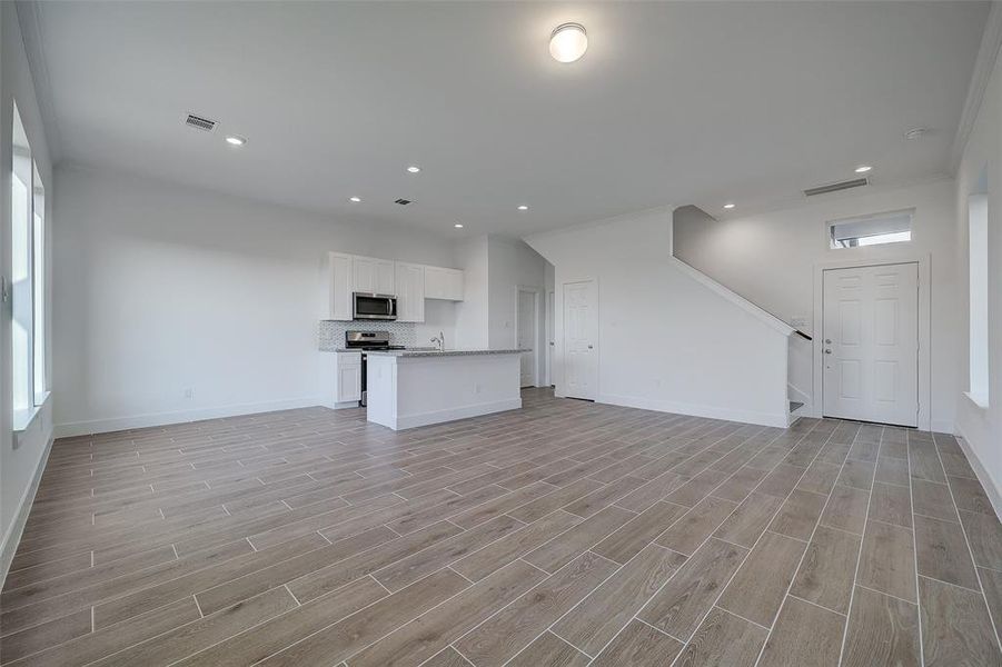 A wider angle creates a better overall view of this incredible living room. The space is bathed in natural sunlight from large windows overlooking the yard. Photos reflect finishes from another home from the same builder