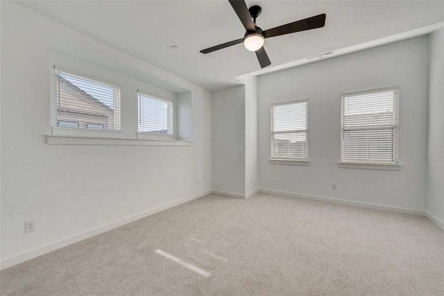 Carpeted empty room featuring a wealth of natural light and ceiling fan