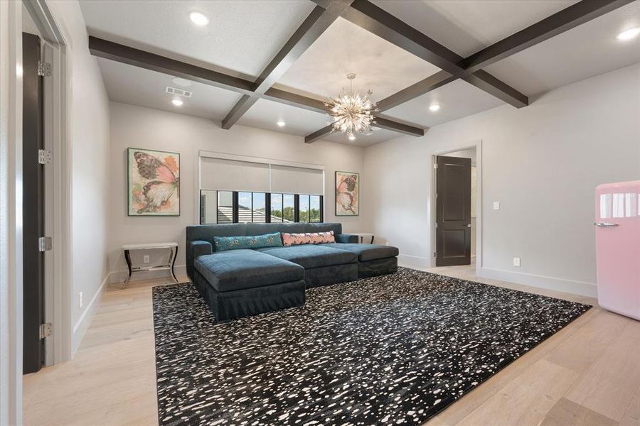 Living room featuring an inviting chandelier, beamed ceiling, coffered ceiling, and light hardwood / wood-style floors