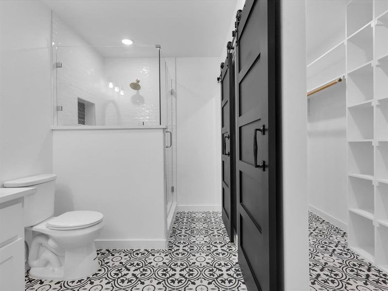 Bathroom featuring tile patterned flooring, toilet, and a shower with door