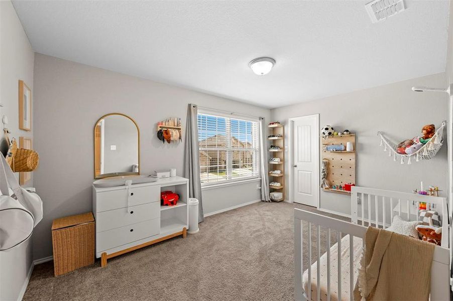 Bedroom featuring light carpet and a nursery area