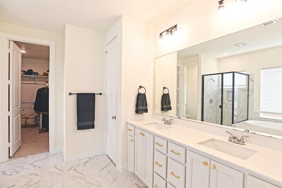 Primary bathroom featuring tile flooring, shower with separate bathtub, and double vanity