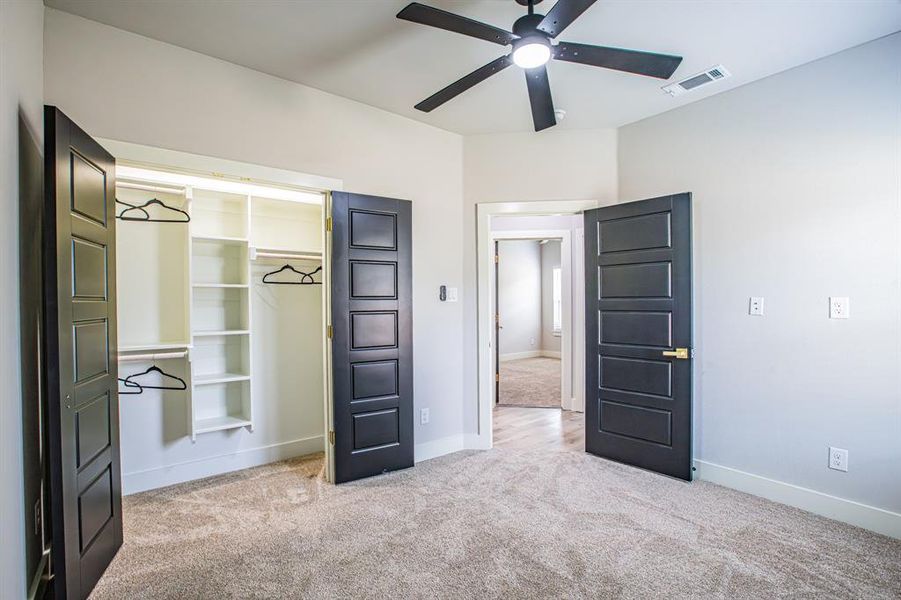 Unfurnished bedroom featuring light colored carpet, a closet, and ceiling fan