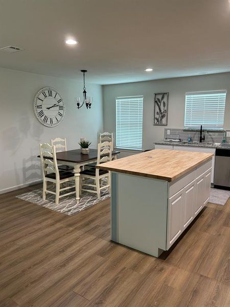 Kitchen with wood counters, decorative backsplash, a center island, white cabinetry, and dark hardwood / wood-style flooring