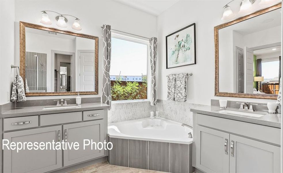 Bathroom with dual vanity, a healthy amount of sunlight, and a bathtub