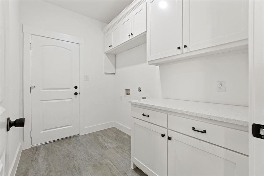 Clothes washing area with hookup for a washing machine, cabinets, and light hardwood / wood-style flooring