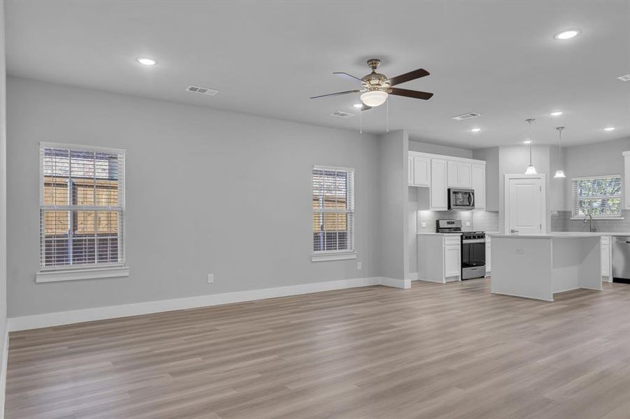 Unfurnished living room with ceiling fan, sink, and light hardwood / wood-style floors