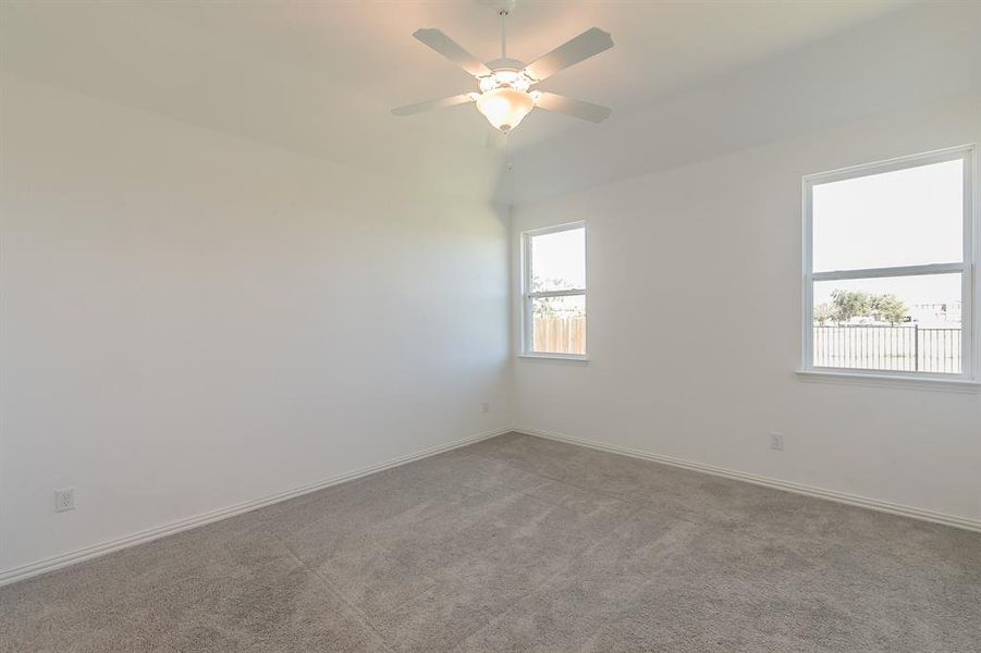 Carpeted empty room featuring a healthy amount of sunlight and ceiling fan