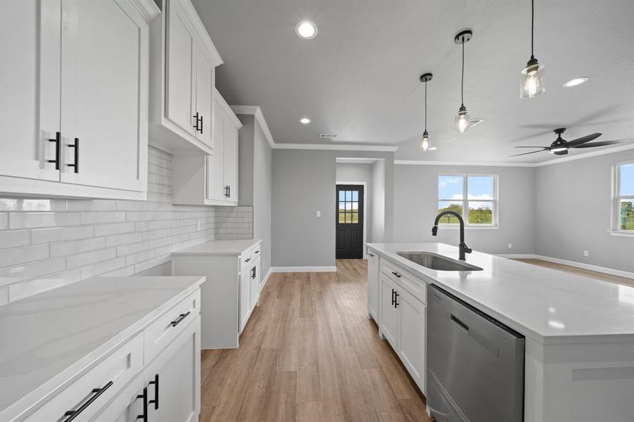 Kitchen with light hardwood / wood-style flooring, sink, an island with sink, dishwasher, and ornamental molding