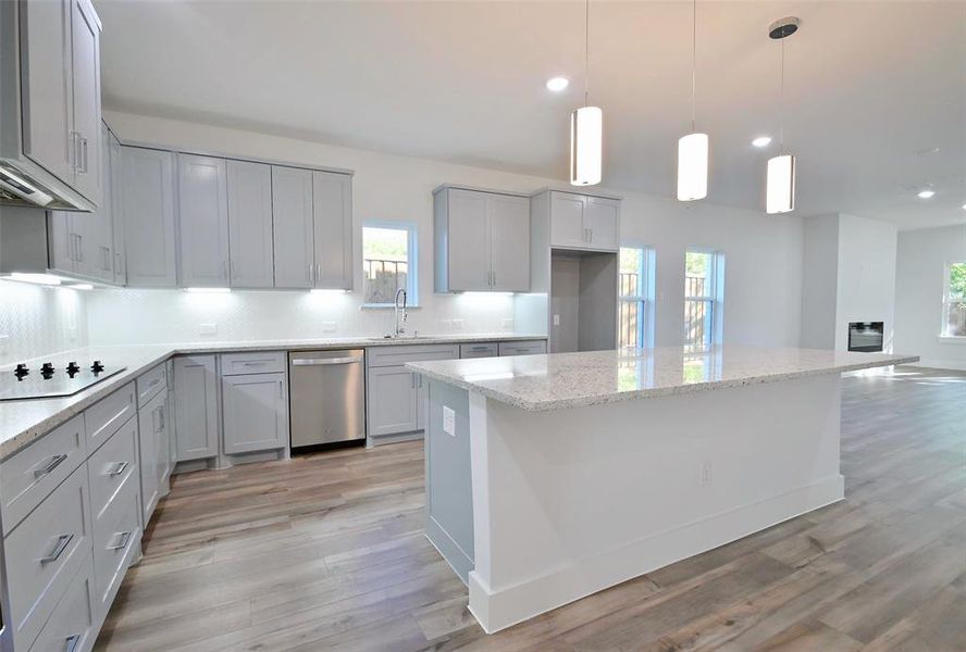 Kitchen with dishwasher, light hardwood / wood-style floors, a kitchen island, decorative light fixtures, and black electric cooktop