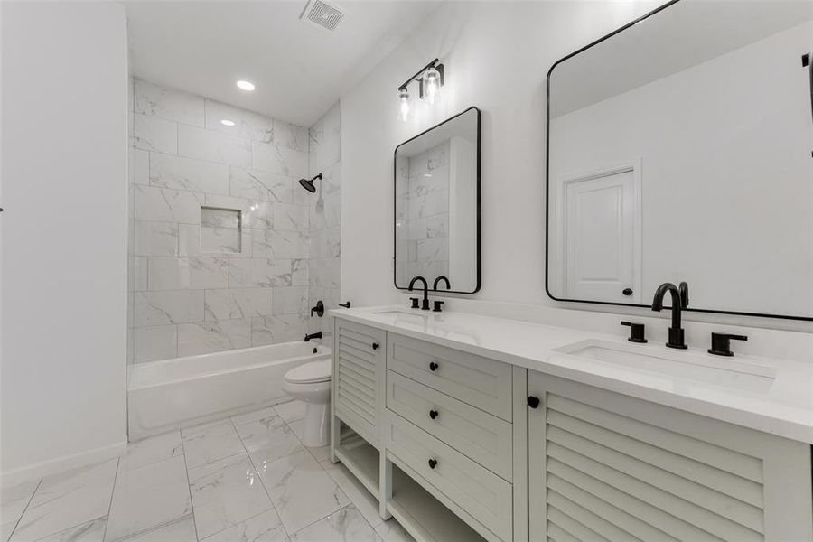 Full bathroom featuring tiled shower / bath combo, vanity, and toilet