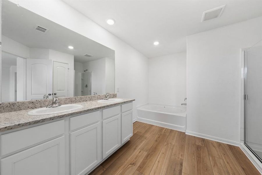 The primary bathroom includes granite countertops, double vanities, luxury vinyl plank flooring and enclosed water closet.