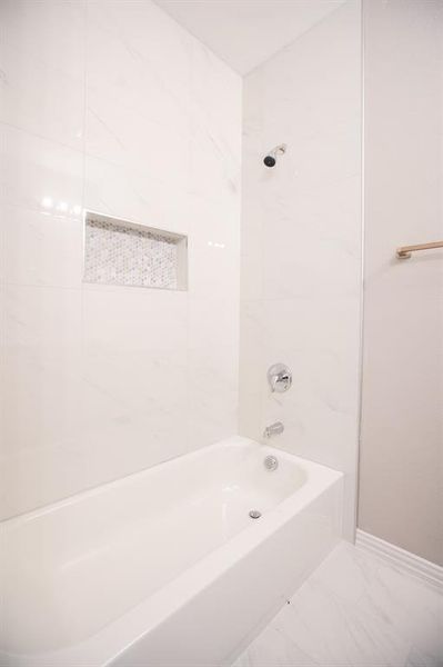 Bathroom featuring tiled shower / bath and tile patterned flooring
