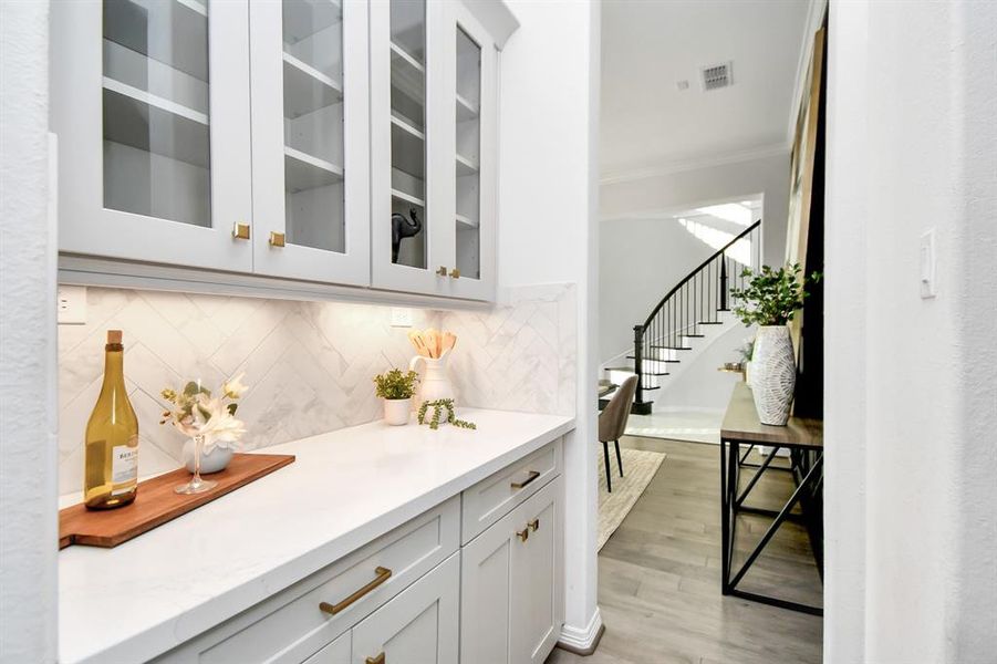 Luxury and functionality, from thedining room to the kitchen is abutlers pantry featuring more storagewith uppers and lowers, lightcounters, upgraded backsplash andcountertops as well as upgradedupper doors with glass and upgradedhardware accenting this luxuryhome.