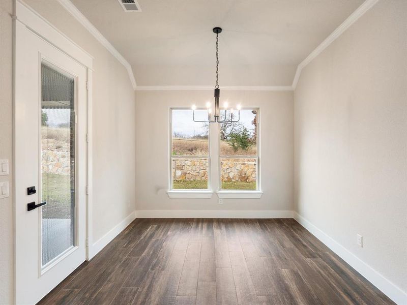 Unfurnished dining area featuring ornamental molding, dark hardwood / wood-style flooring, and a chandelier