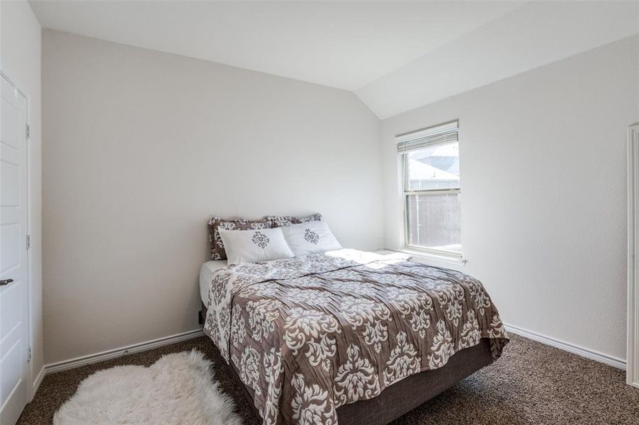 Bedroom with vaulted ceiling and dark carpet