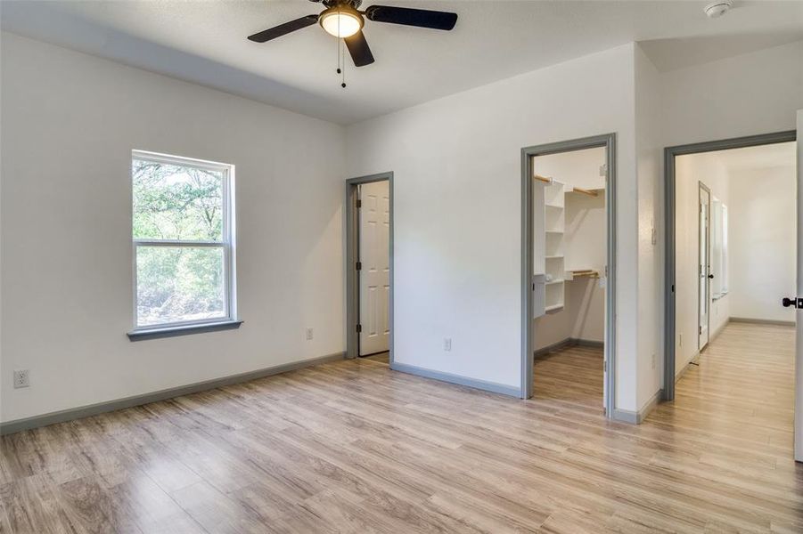 Unfurnished bedroom with light wood-type flooring, a spacious closet, ceiling fan, and a closet