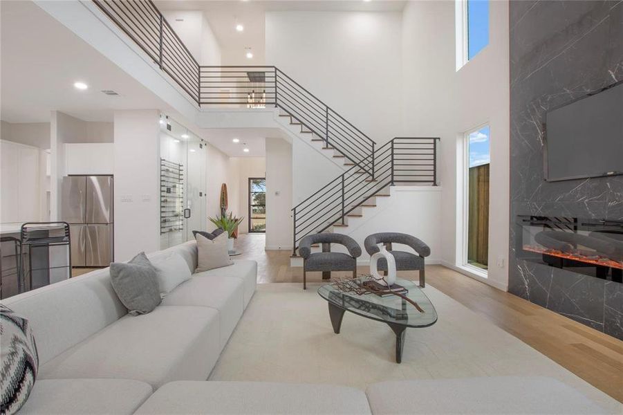 Living room featuring light hardwood / wood-style flooring, a fireplace, and a towering ceiling