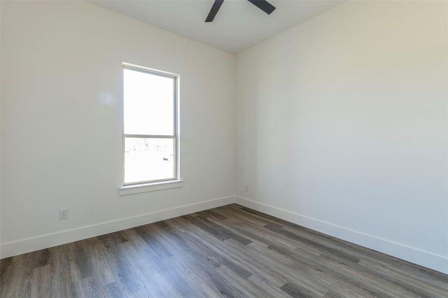 Empty room featuring ceiling fan and dark hardwood / wood-style flooring