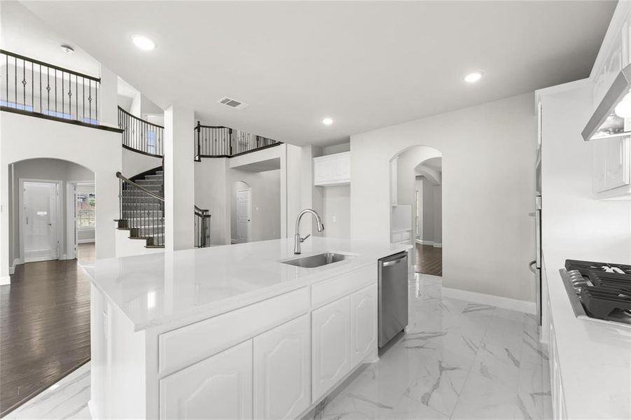 Kitchen with light wood-type flooring, sink, white cabinets, gas cooktop, and stainless steel dishwasher