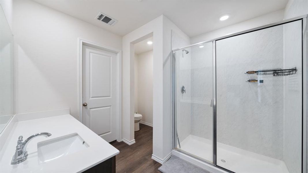 Bathroom featuring walk in shower, hardwood / wood-style flooring, vanity, and toilet