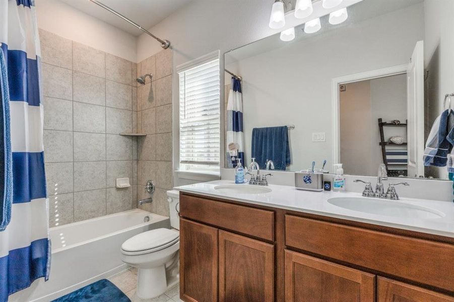 Full bathroom with shower / bathtub combination with curtain, tile patterned floors, vanity, and toilet