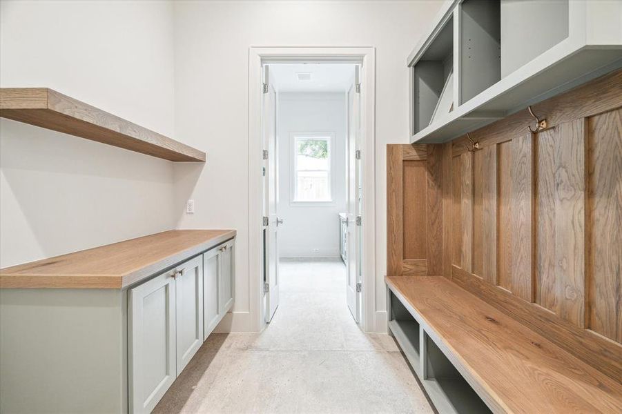 A spacious mud room is the perfect drop zone for kids shoes, sports equipment, etc. Sage green cabinetry is topped with stained wood accents tying in the stained wood features throughout the home.