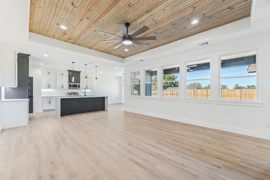 Unfurnished living room with a tray ceiling, a wealth of natural light, and light hardwood / wood-style floors